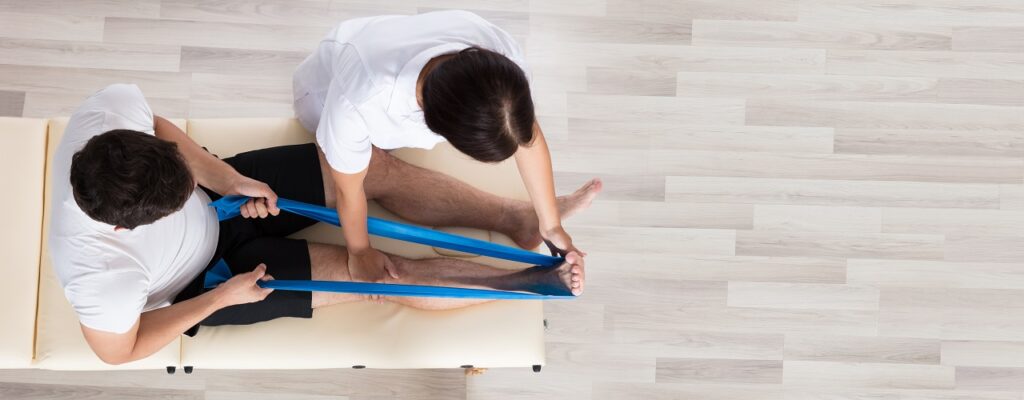 Female Therapist Assisting Patient While Exercising