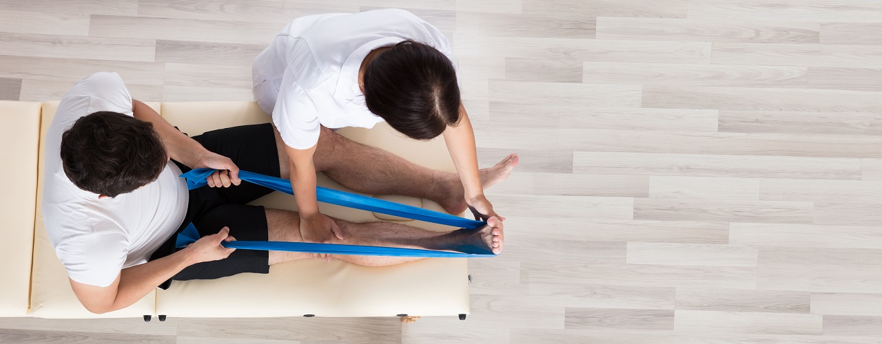 Female Therapist Assisting Patient While Exercising